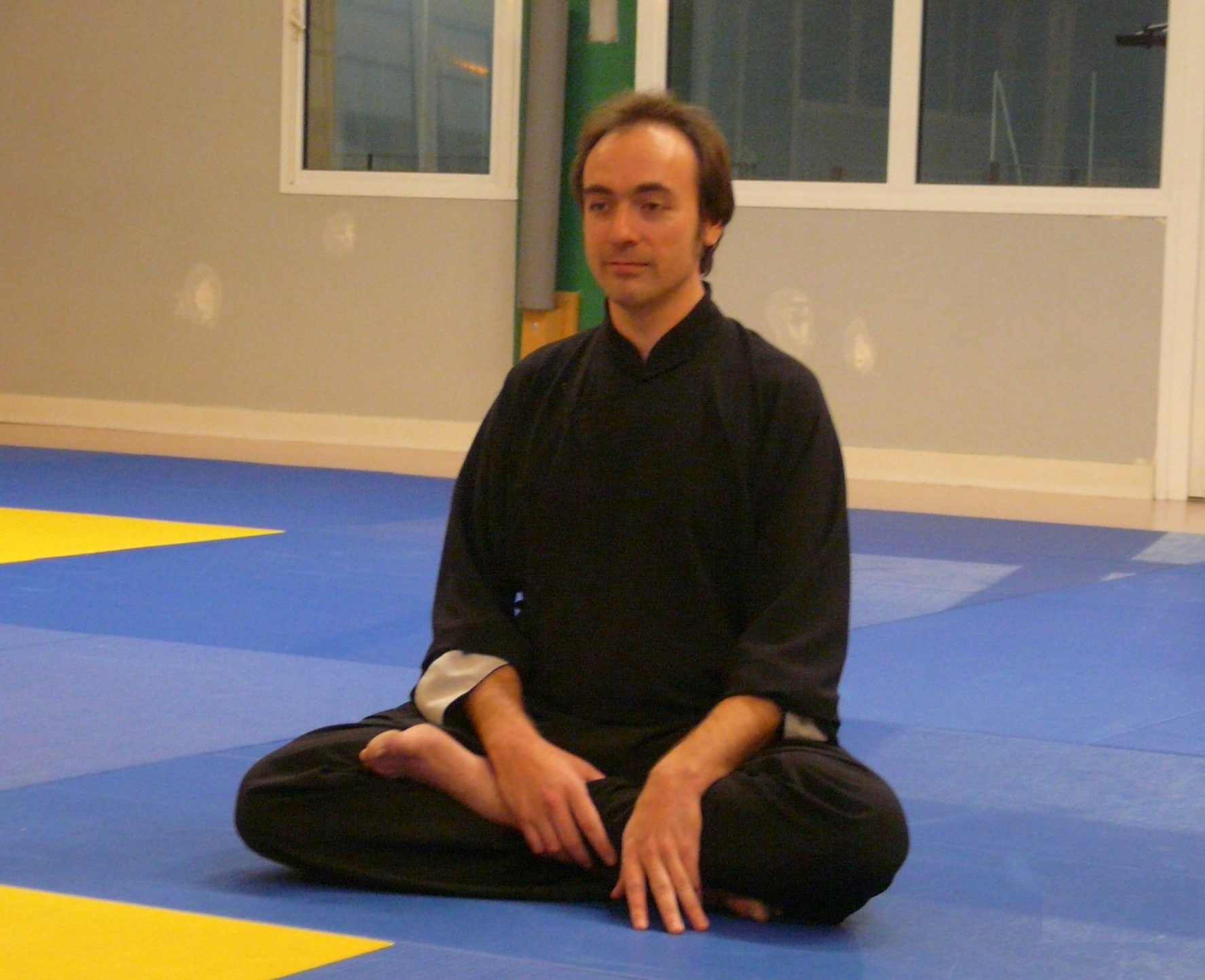 Altaïr Dejoux, enseignant, assis en méditation au dojo